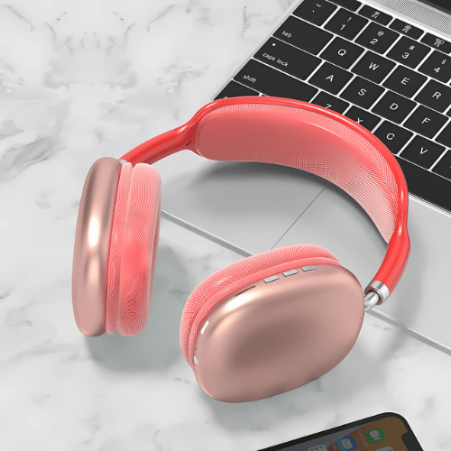 Pink headphones on a marble surface with a laptop in the background