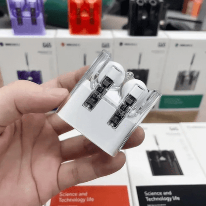 White earbuds in clear case held by a hand with blurred store background